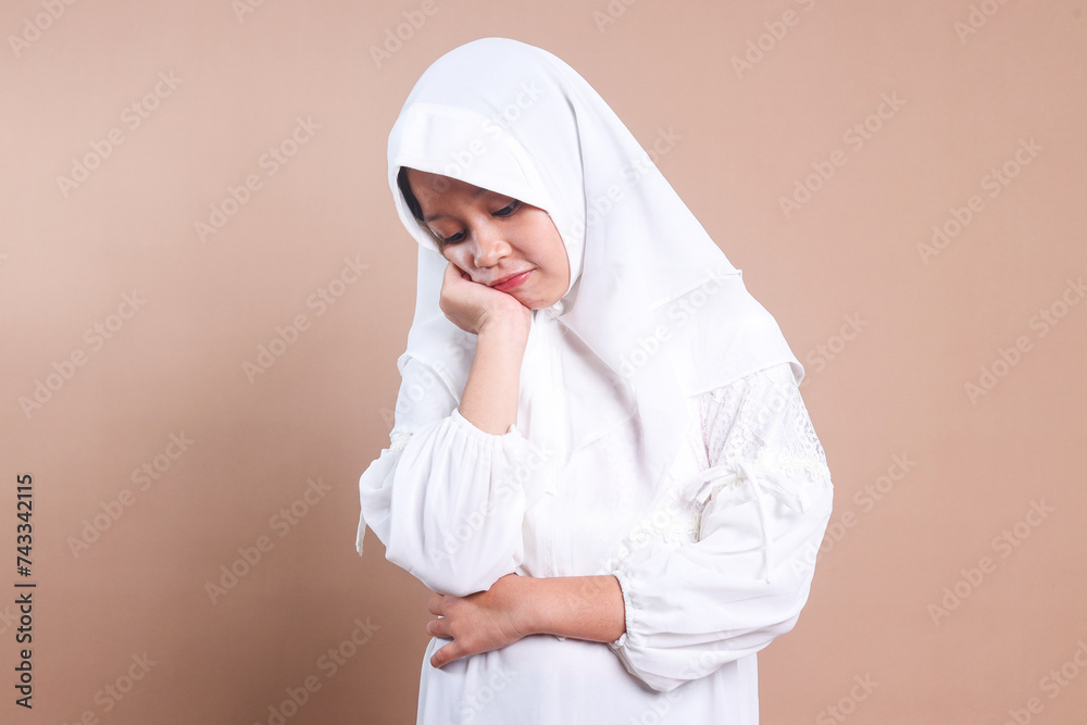 Young Asian muslim girl wear hijab put hand on cheek feeling sad and lonely