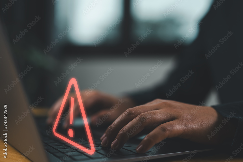 Obraz premium Businessman using computer laptop with triangle caution warning sing for notification error and maintenance concept..