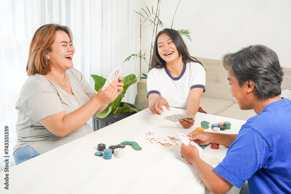 Portrait of Asian people playing card games and having fun at home, laughing happily. Close up. Portrait of Asian people playing card games and having fun at home, laughing happily. Close up.