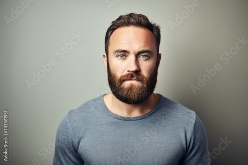 Portrait of a handsome young man with beard and mustache over grey background. © Inigo