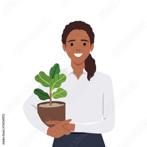 Young woman in cozy room holds pot with a plant in her hands. Concept of growing and caring house plants. Gardener takes care of the home garden