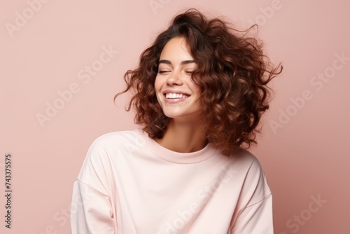 Portrait of a beautiful young woman with curly hair on a pink background © Inigo