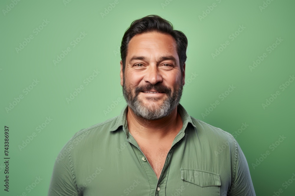 Portrait of a smiling middle-aged man with beard and mustache against green background Portrait of a smiling middle-aged man with beard and mustache against green background