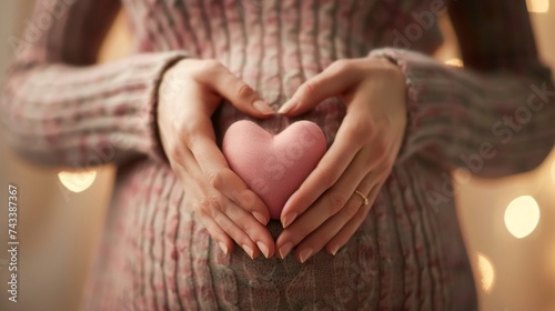 A pregnant woman in a cozy sweater forming a heart shape over her belly with her hands, perfect for maternity, love, and family growth themes.