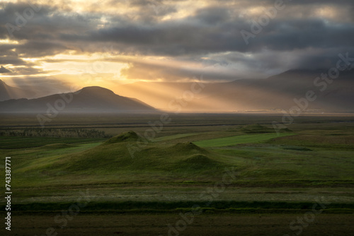 Colorful sunset and lightrays over the hills and farmlands of rural Iceland