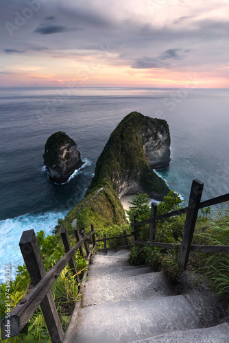 Sunset view at the famous Kelingking Beach at Nusa Penida island and steep stairs leading down to the famous beach and the scenic cliffs