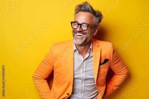 Portrait of a happy mature man in orange jacket over yellow background © Inigo