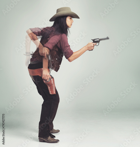 Western, cowboy and woman with gun in studio for motion, speed and shooting with standing ready. Female person, weapon and serious expression with pistol for character, halloween and costume design photo