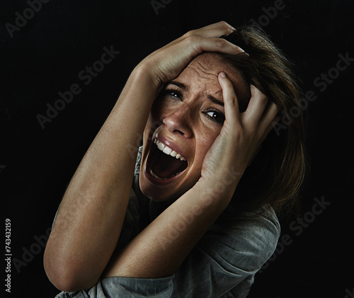 Portrait, horror and fear with woman screaming in studio on black background for reaction to danger. Face, stress and mental health with scared young person in dark for phobia, nightmare or terror photo