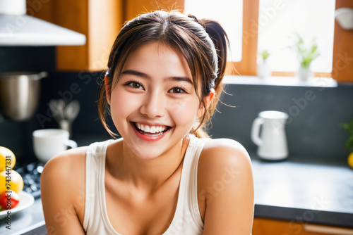キッチンで前向きに微笑む美しい髪を結んだ日本人女性 photo