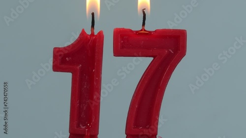 close up on timelapse melting a red number seventeenth birthday candle on a white background.
