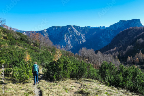 Hiker woman on idyllic hiking trail along alpine terrain near mount Hochblaser in Eisenerz, Ennstal Alps, Styria, Austria. Scenic view of majestic mountain peaks. Alpine landscape. Wanderlust concept photo