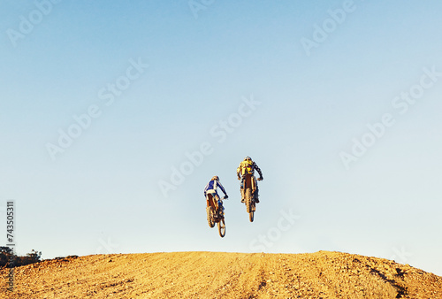 Rear view, racer and motorcycle in action for competition on dirt road with performance, challenge and adventure. Motocross, motorbike or dirtbike driver with jump stunt on offroad course for racing photo