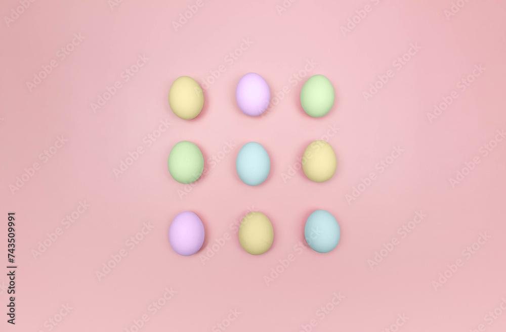 Top view of nine colourful eggs on pink background. Creative easter composition, flat lay, copy space. Spring, modern and minimalist. 