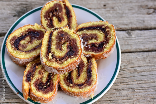 Home made swiss roll cake  with organic eggs and  peach jam covered with sugar on wooden background.  Healty natural dessert