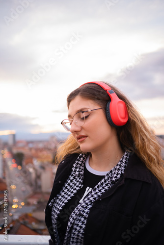 Sexy young woman listening to music on headphones in the city