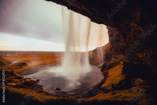 Beautiful view of Seljalandsfoss in Iceland on summer morning. View behind the water curtain of the waterfall.