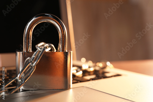 Cyber security. Laptop with padlock and chain on table, closeup. Space for text