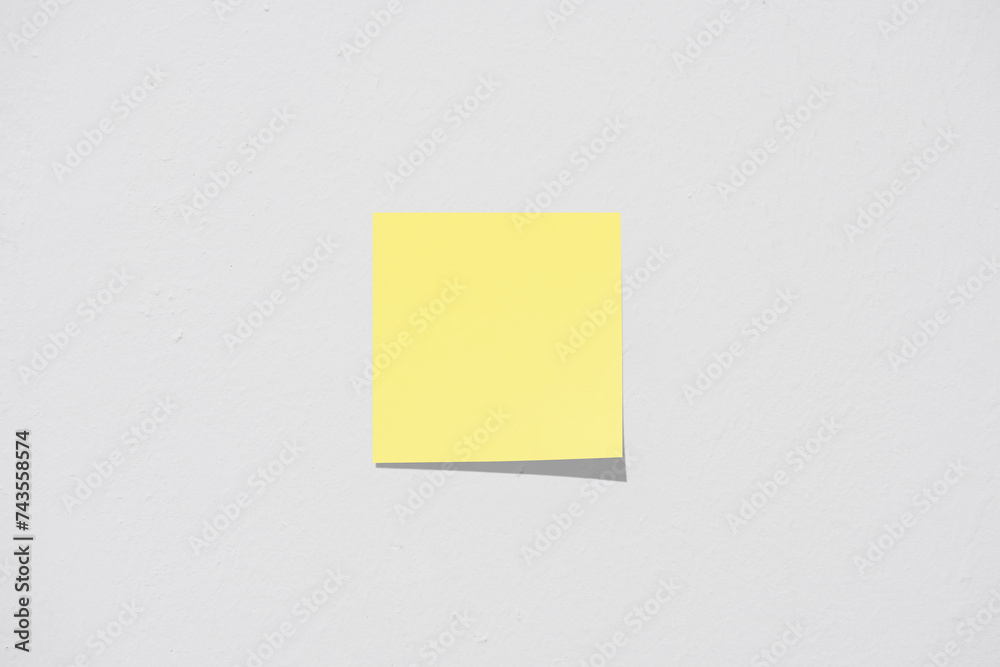 Yellow sticky note on white wall Yellow sticky note on white wall