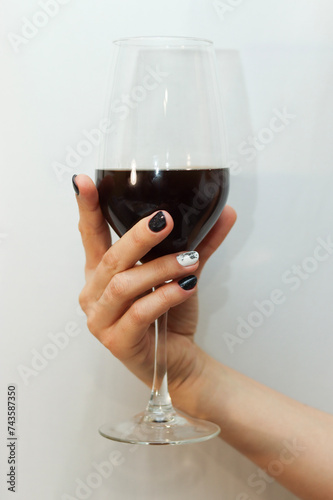 Woman hand holding glass of red wine. Elegant minimal aesthetic. Wine tasting concept.