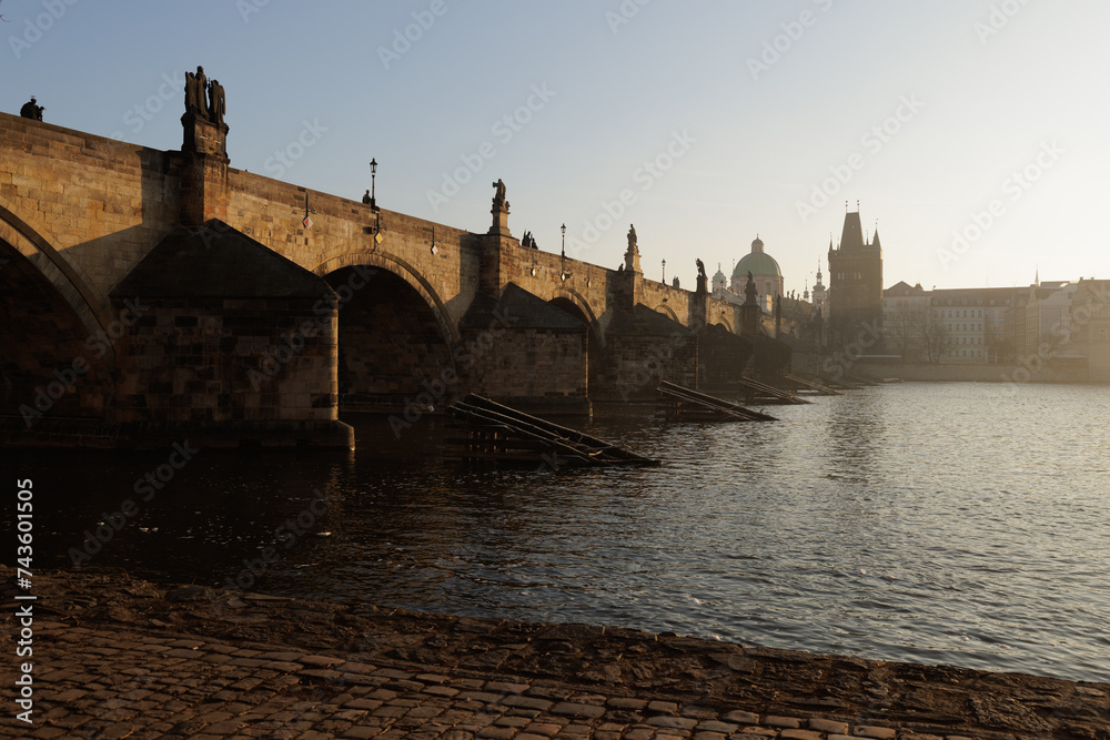 A Charles bridge crossing over a body of water with a city in the background