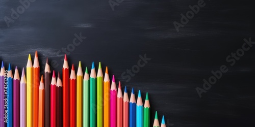 Colored pencils on chalkboard background. Top view and copy space