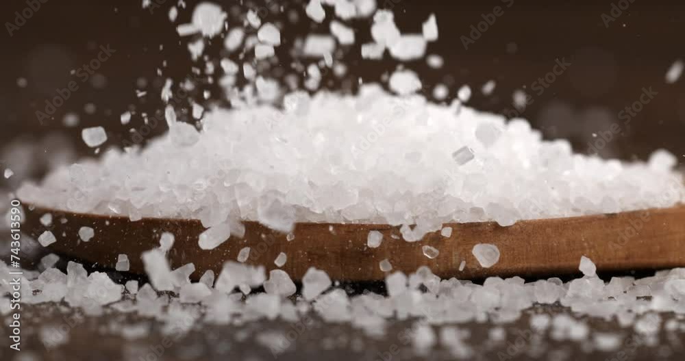 Super slow motion macro of granulated rough crystal himalayan salt grains in wooden plate at 1000 fps.