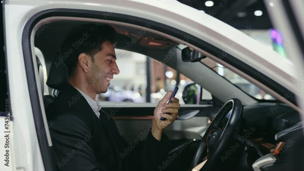 Cheerful Handsome Bearded Car Owner Enjoying Funny Videos on Phone. Young Businessman Rejoices at the Good News Sitting in a New Car. Technology and Business Concept Cheerful Handsome Bearded Car Owner Enjoying Funny Videos on Phone. Young Businessman Rejoices at the Good News Sitting in a New Car. Technology and Business Concept