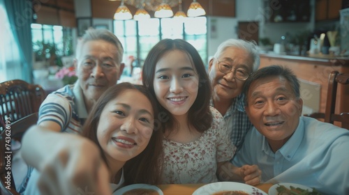 Selfie shot   asian teenage girl taking selfie with big family and grand parents on dinner.