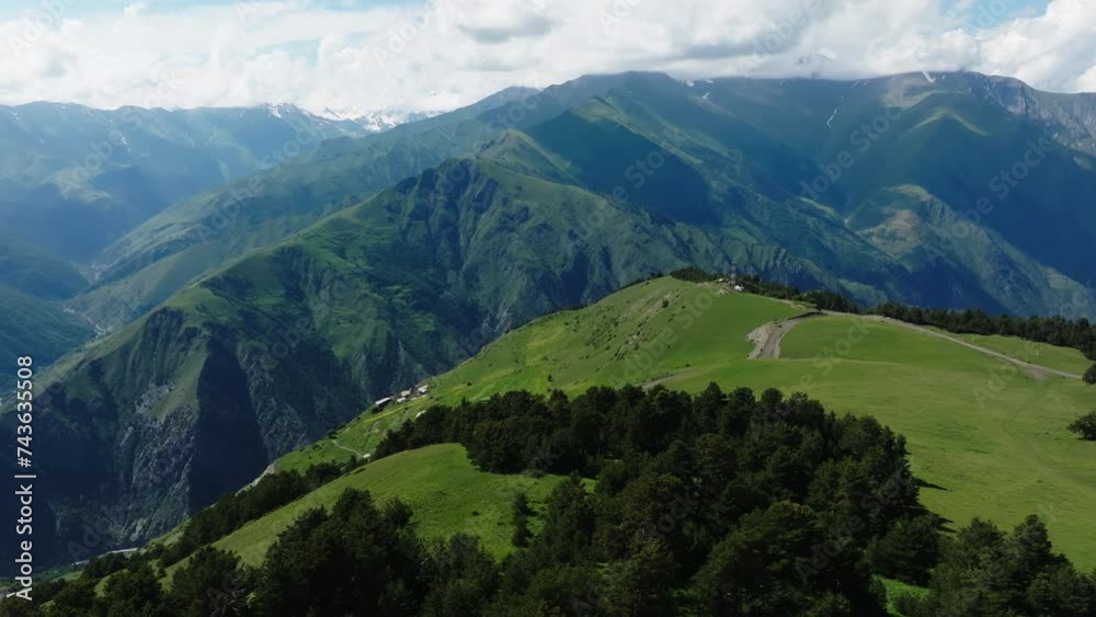 Panoramic view of mountain ranges with lush valleys and a solitary trail under a cloudy sky Panoramic view of mountain ranges with lush valleys and a solitary trail under a cloudy sky