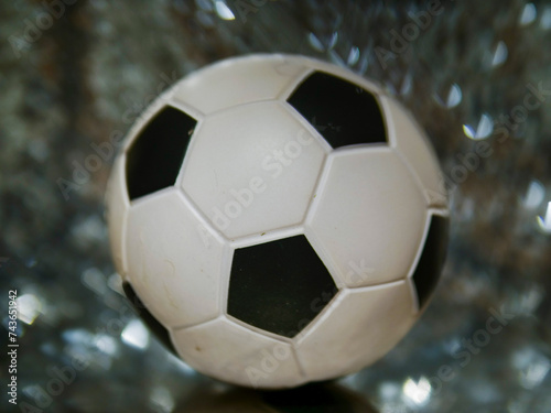 Classic soccer or football ball in focus. Busy background with glitter abstract bokeh. Sport theme image.