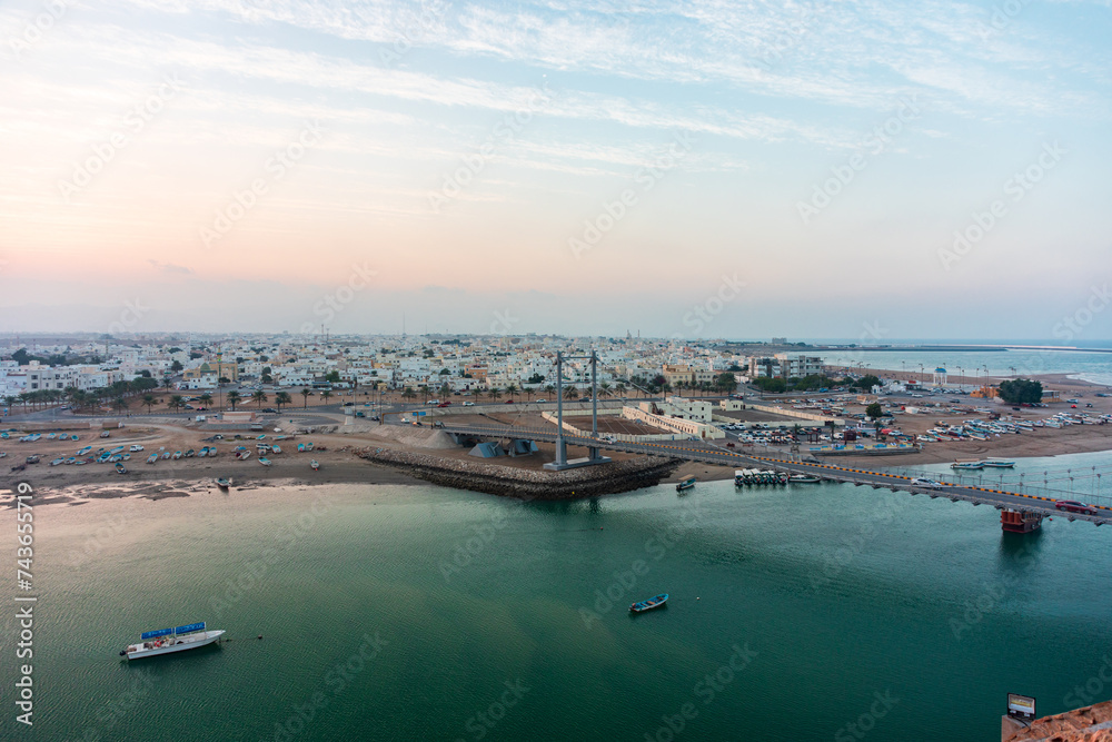Panoramic view on west part of the Sur city in golden hour. Al Ayjah Bridge, Sur, Oman