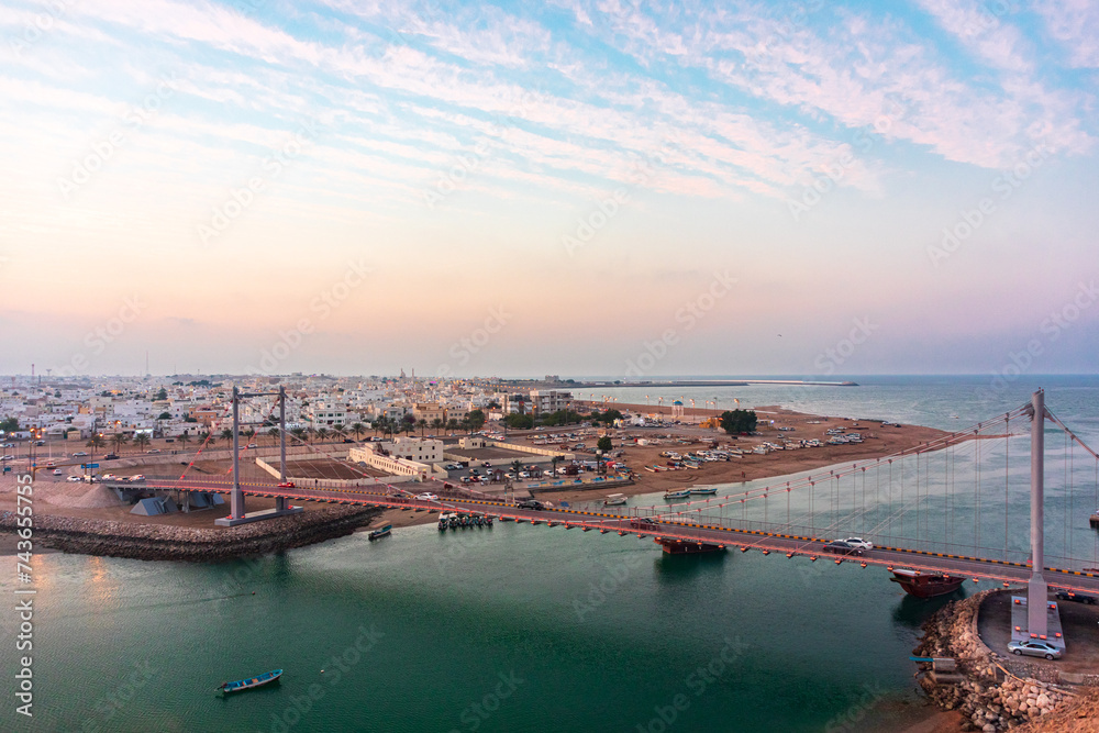 Fototapeta premium Panoramic view on west part of the Sur city in golden hour. Al Ayjah Bridge, Sur, Oman