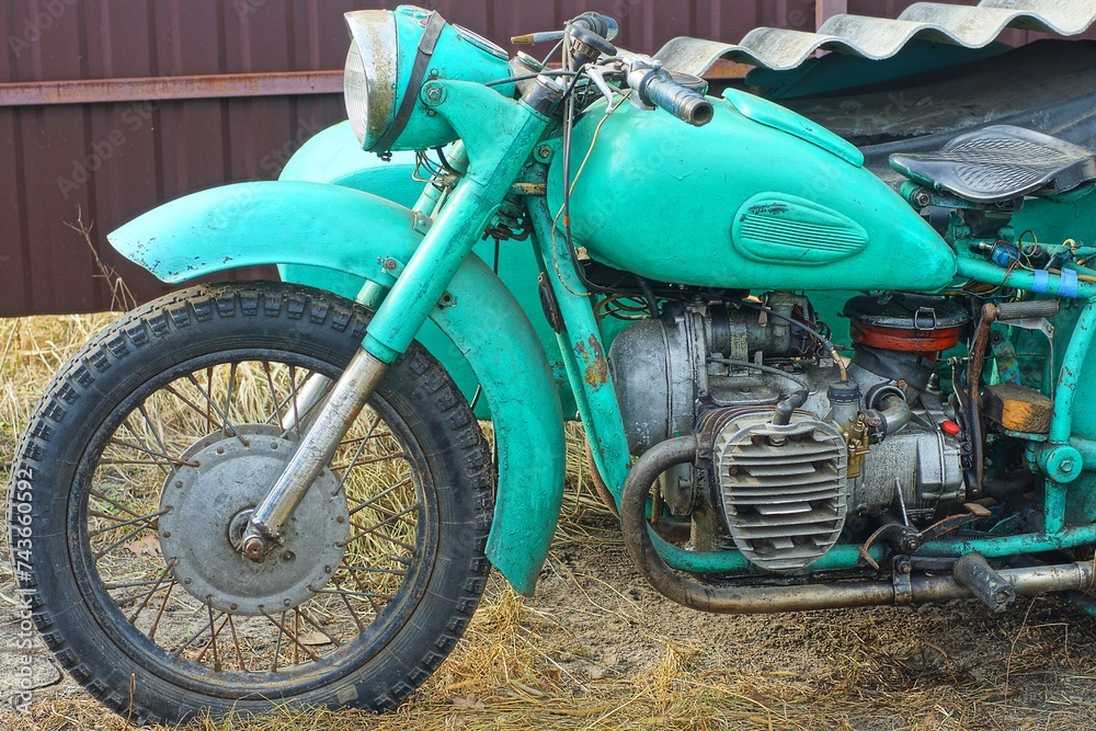 one retro green  iron old rusty broken dirty motorcycle stands on the ground on the street during the day