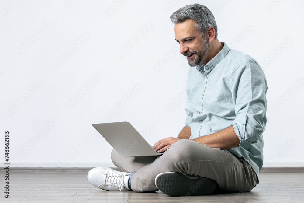Bearded man looking at laptop computer for online work isolated on white.