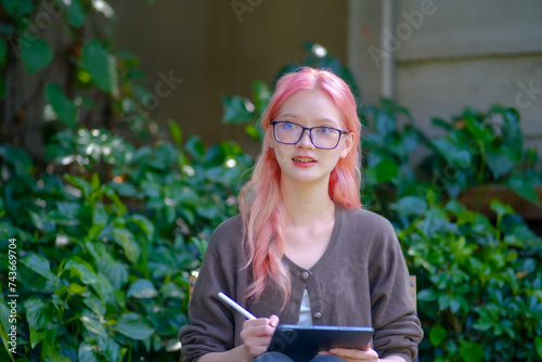 Cute pink hair girl drawing on digital tablet in garden, Woman Doing Freelance Work in Garden, woman with digital tablet with graffiti artwork