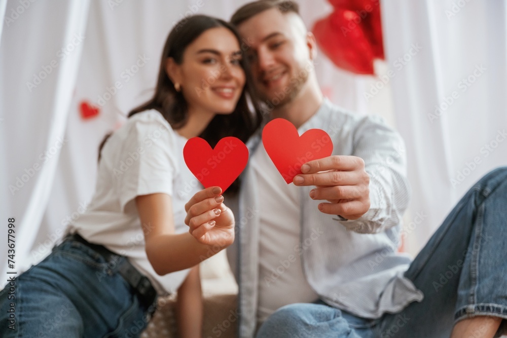 Holding paper hearts. Young couple are together at home