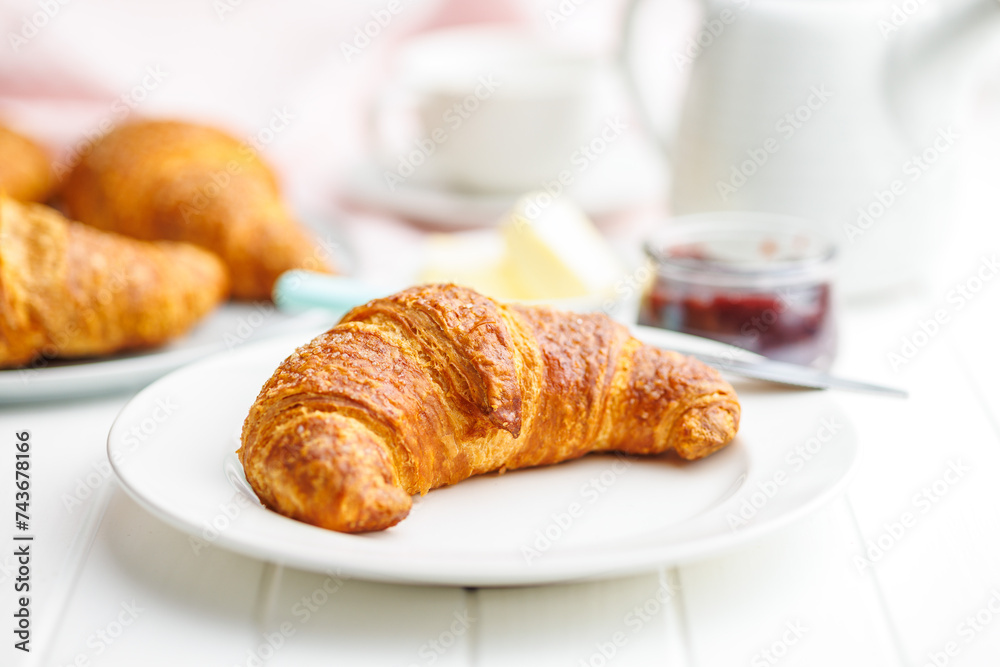 Baked tasty croissant on plate on white table. Baked tasty croissant on plate on white table.