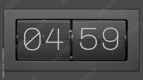 Flip clock quickly flips. Retro flip clock changing from 04:59 to 05:00. Slow motion.   photo