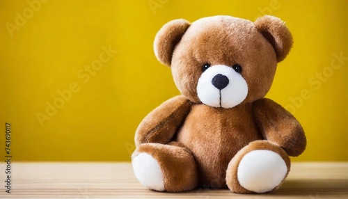 Beautiful brown bear, wool toy sitting, bright yellow backdrop.