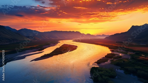 Breathtaking sunset over a winding river with mountainous landscape in the background.
