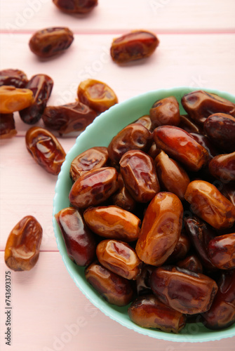 Fresh dates in mint bowl on pink background. Vertical photo