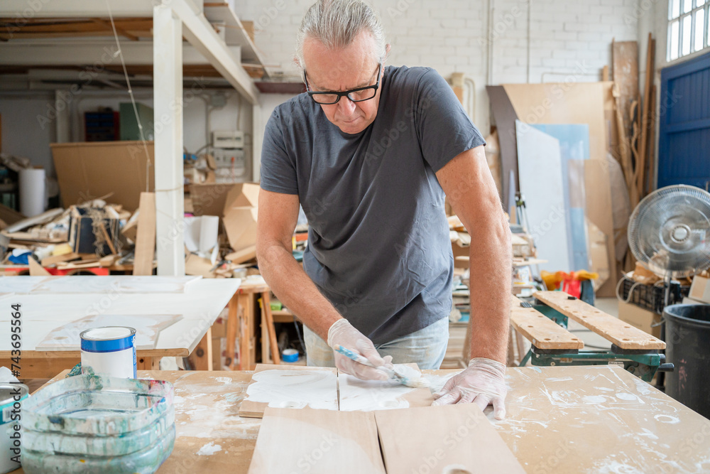 Senior artist working on wood craft at workshop painting wooden furniture. High quality photo Senior artist working on wood craft at workshop painting wooden furniture. High quality photo