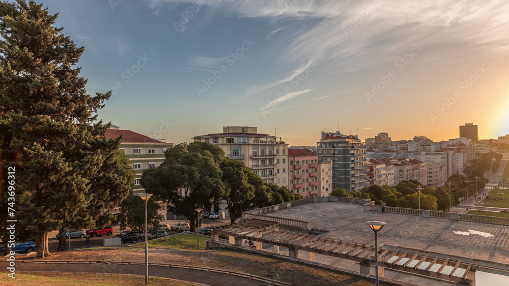 Panorama showing sunset over lawn at Alameda Dom Afonso Henriques and the Luminous Fountain aerial timelapse in Lisbon.