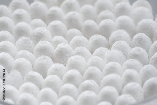 Macro view of white cotton ear cleaning buds arranged in white backgroud nicely in a container