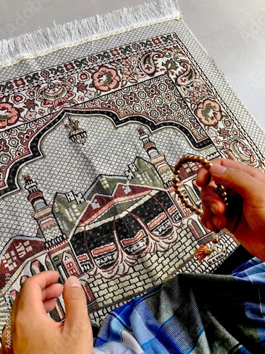 Close up of A portrait of an asian muslim man pray, the pray name is sholat, regards end of sholat. Using blue sarong and gray sajadah photo