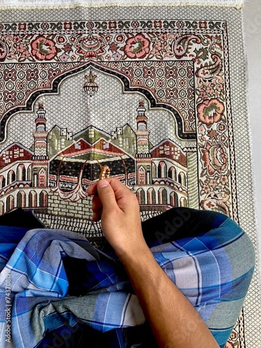 Close up of A portrait of an asian muslim man pray, the pray name is sholat, regards end of sholat. Using blue sarong and gray sajadah photo