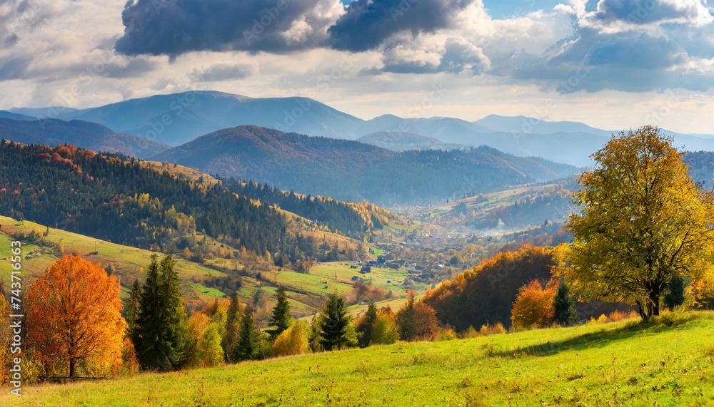 rural area of carpathian mountains in autumn village in the distant valley trees on the hills in fall colors distant mountain ridge beneath a sky with clouds