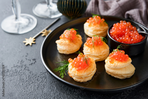 Salmon red caviar toast. Christmas canape or toast with red caviar on black plate on dark background. Idea to xmas snack. Gourmet food. Texture of caviar. Seafood.