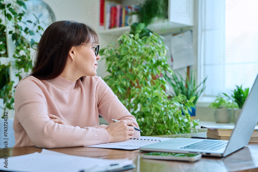 Middle-aged woman working at computer laptop in home office Middle-aged woman working at computer laptop in home office